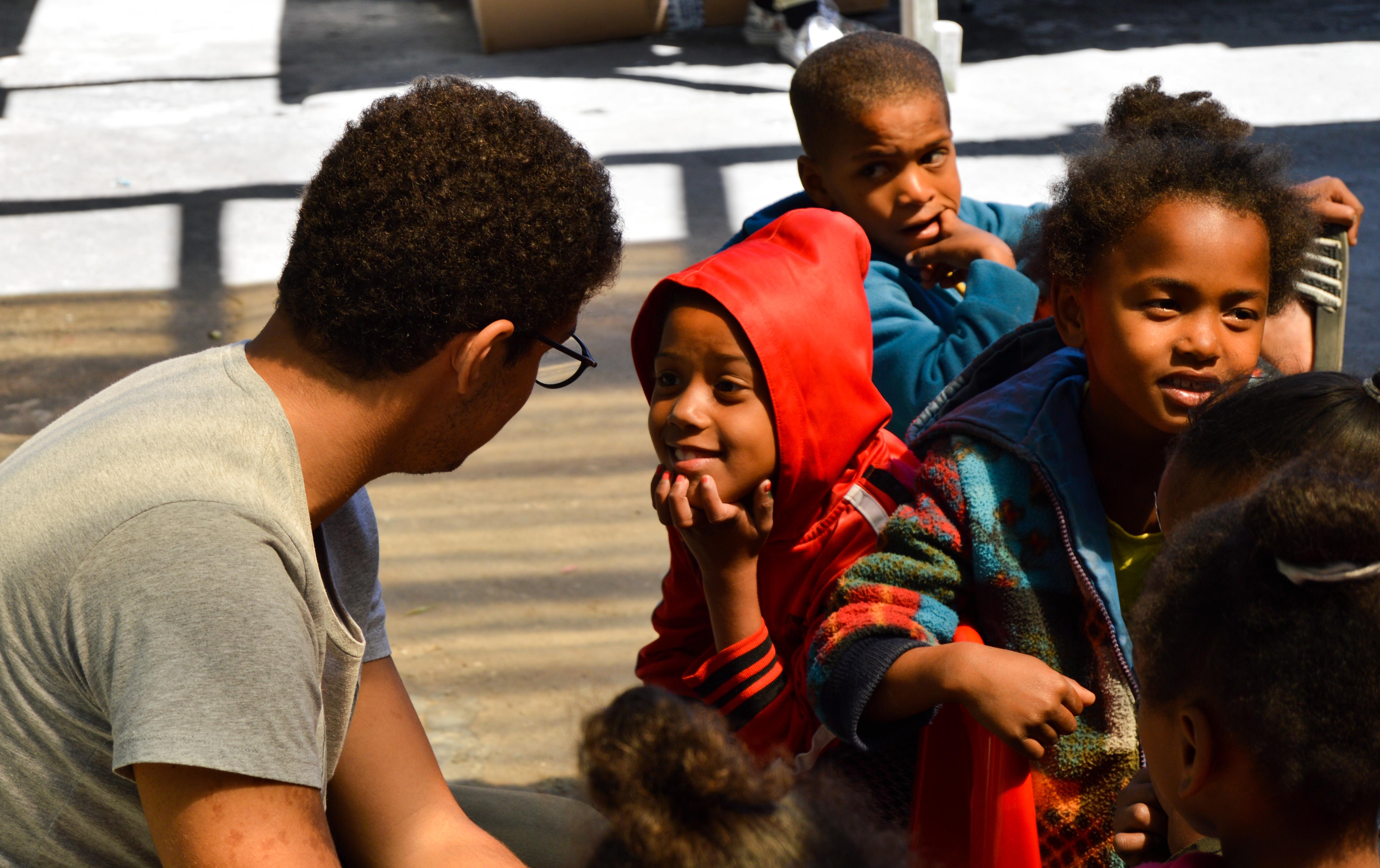 A high school student volunteering with children in South Africa speaks to a local child A student spends his summer vacation volunteering with children in South Africa as part of Projects Abroad's placement for teenagers
